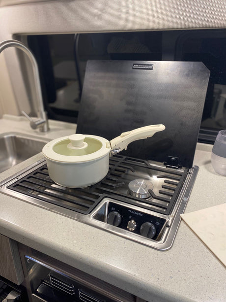 Compact RV rental kitchen with a pot on the Dometic stovetop and sink. Ready for cooking meals on your adventure.