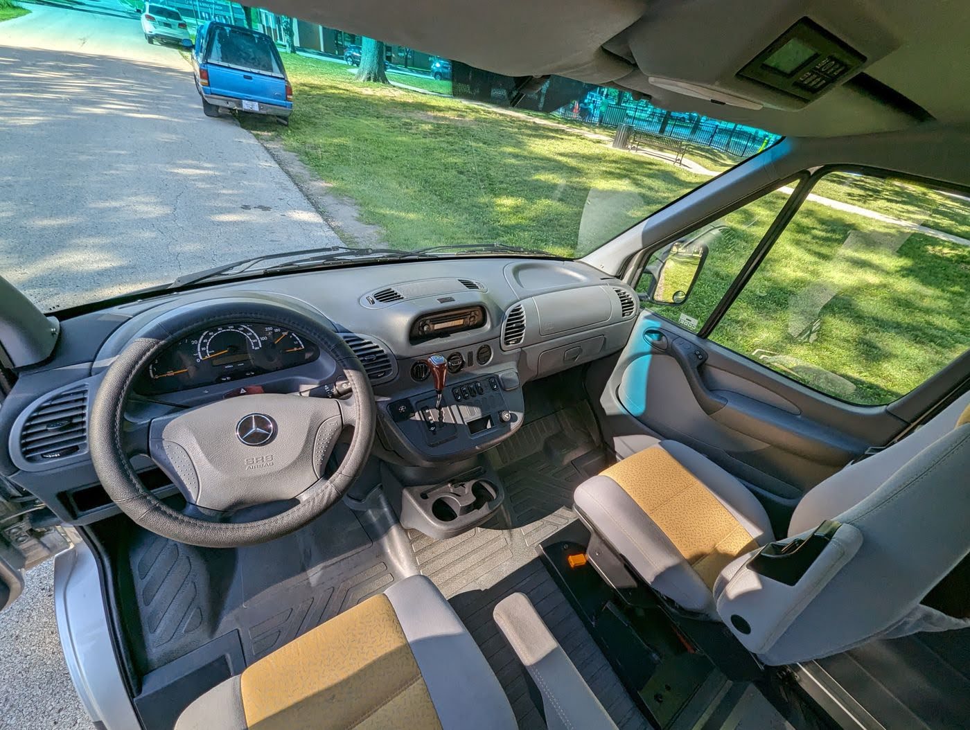 Step into this RV rental van! View of the spacious interior, dashboard, steering wheel, and front seats with distinctive upholstery.