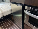Modern rv rental interior showcasing a compact kitchen with a built-in stainless steel refrigerator and microwave oven.