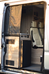 Overhead view of a modern RV rental interior, showing kitchen area with fridge, control panel, and plush seating for comfortable travel.