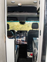 Inside an RV rental, showing the front cabin with an overhead bed and safety features like a smoke detector.