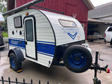 A white and blue Sunray Classic teardrop camper, seen parked, would make a great RV rental for camping.