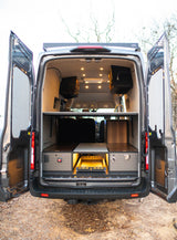 Inside a modern RV rental van conversion: organized storage, task lighting, and a pull-out kitchen/gear tray for travel.