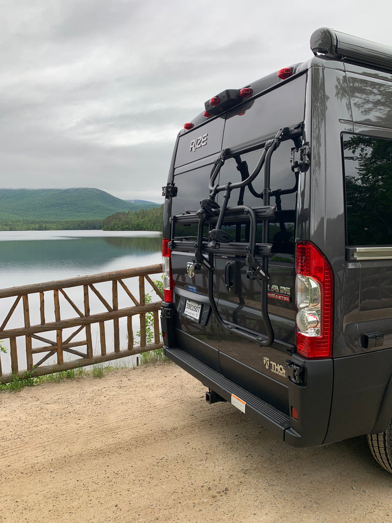 Dark gray Rize camper van with a bike rack by a scenic lake and mountains, perfect for an RV rental outdoor adventure. — photo 4