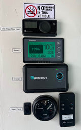 RV rental vehicle control panel displays battery, water, heating, AC, and inverter systems. No smoking/vaping sign visible.