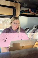 A woman works on her laptop inside an RV rental, an ideal setup for a remote work digital nomad adventure.