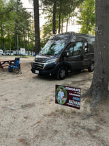 Dark grey RV rental at C20 campsite, next to a picnic table. A yard sign congratulates Nathan, Windham High School Class of 2025.