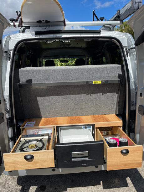 This RV rental features a compact pull-out kitchen with stove, fridge, and a surfboard on the roof rack. Adventure-ready!