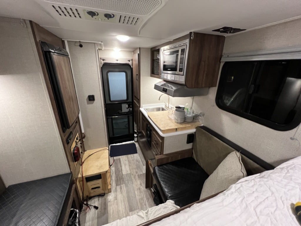  and plush cushions.|Compact RV rental interior featuring a kitchenette (microwave — photo 5