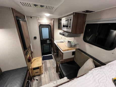RV rental interior: full kitchen, comfy seating/bed, and fridge. Your mobile home for travel adventures.