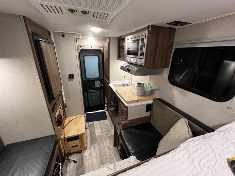  and plush cushions.|Compact RV rental interior featuring a kitchenette (microwave — photo 5