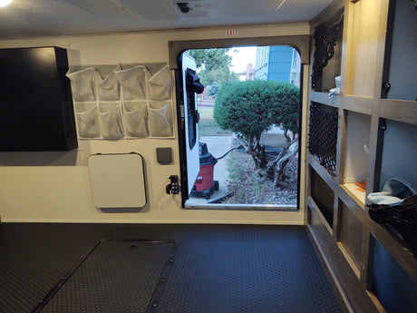 RV rental interior: organized storage, durable flooring, and an open door. This camper setup is ready for adventure.