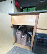**RV rental** water system: portable tanks, pump, and fridge inside a camper kitchen.