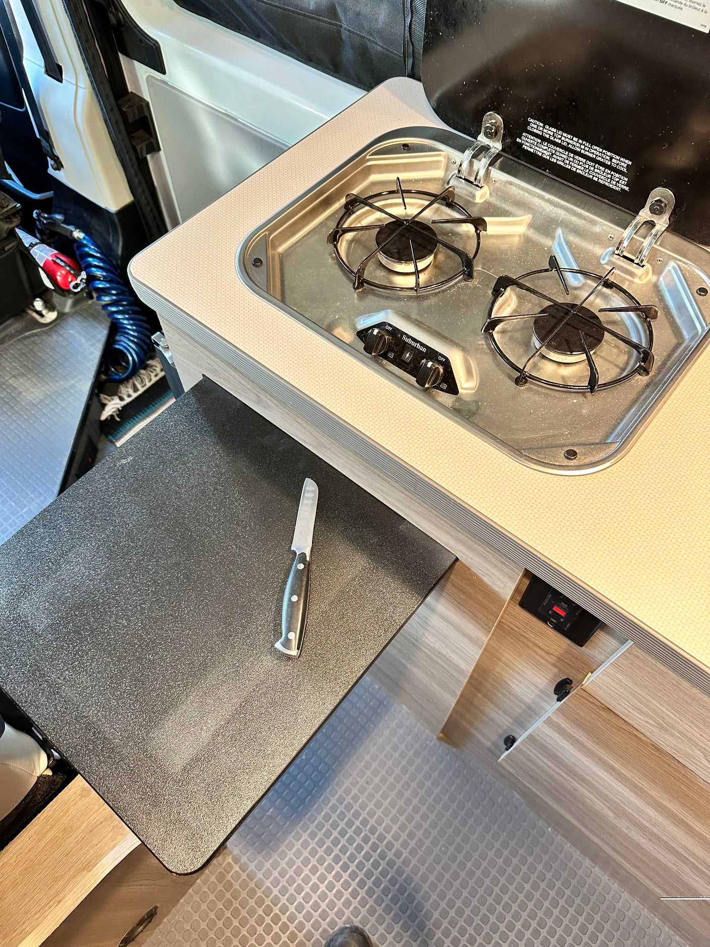 RV rental interior: A compact kitchen area with a two-burner stove, extendable counter, and small knife for cooking.