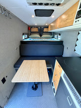 RV rental camper van interior. Enjoy a comfortable bed, dining table, and compact kitchen perfect for road trips.