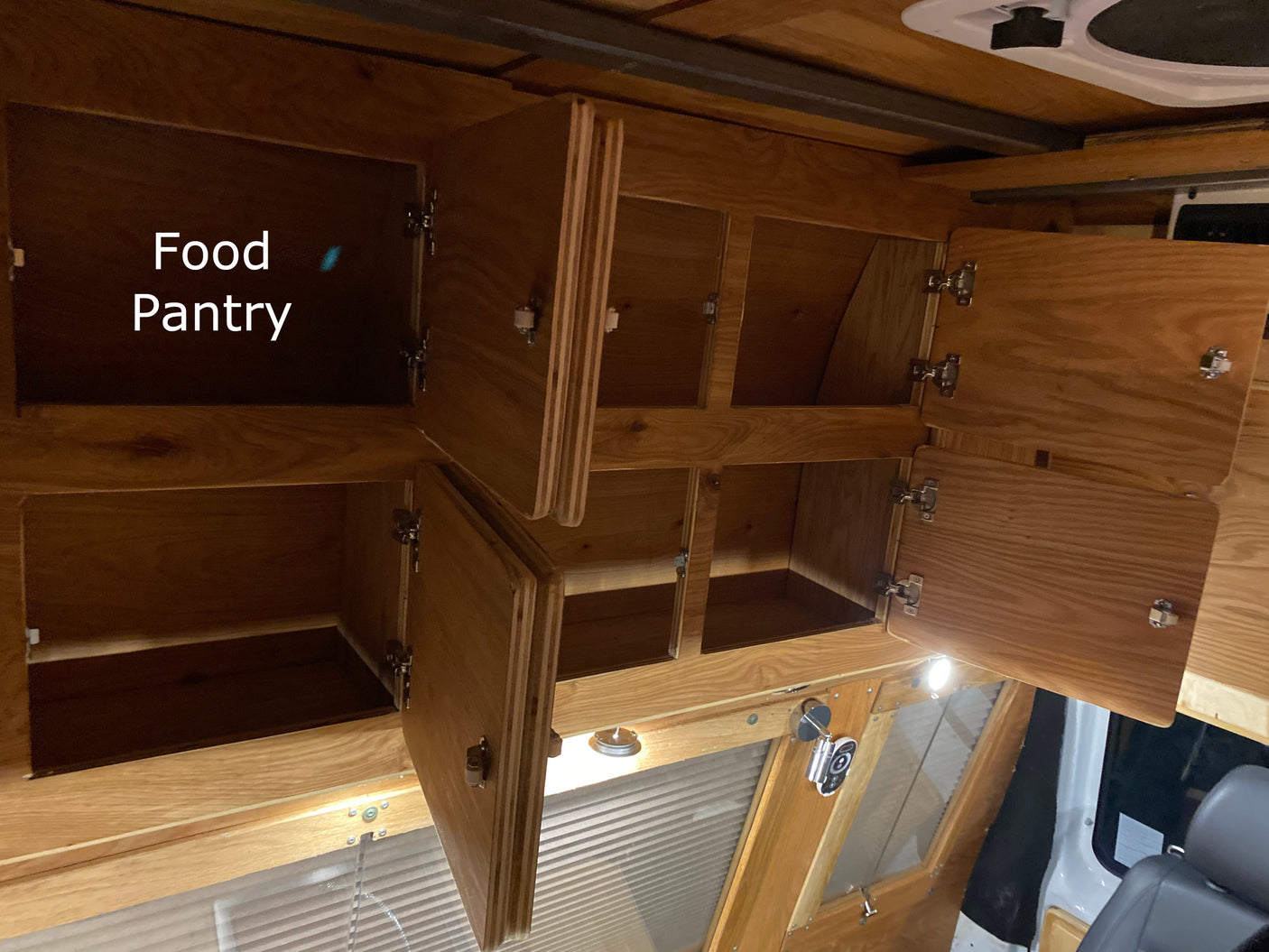 RV rental: Organized wooden food pantry and overhead storage cabinets provide ample space for travel.