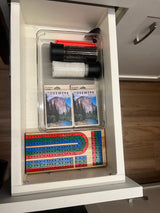 Organized RV rental drawer: salt/pepper grinders, Yosemite playing cards, and a cribbage board, neatly stored.