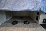 An RV rental's under-bed area has floor mounts for flexible furniture, power outlets, and a vent.