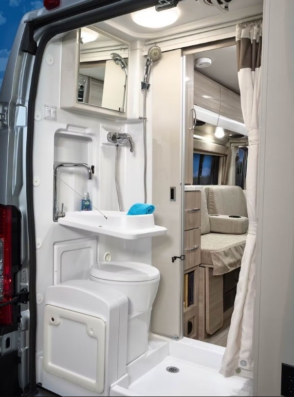  driving on a winding road through green forests. Your road trip awaits!|Cozy rv rental interior featuring swiveled front seats — photo 9