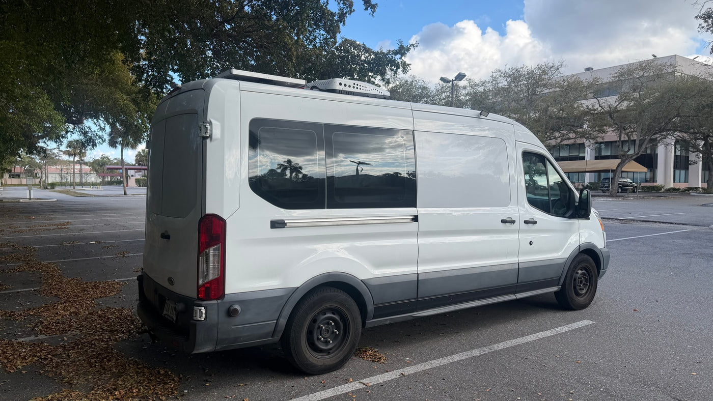  and bed setup for van life adventures.|Inside an RV rental: a plush bed with a white quilted mattress pad & pillows. View to front seats & dashboard — photo 12