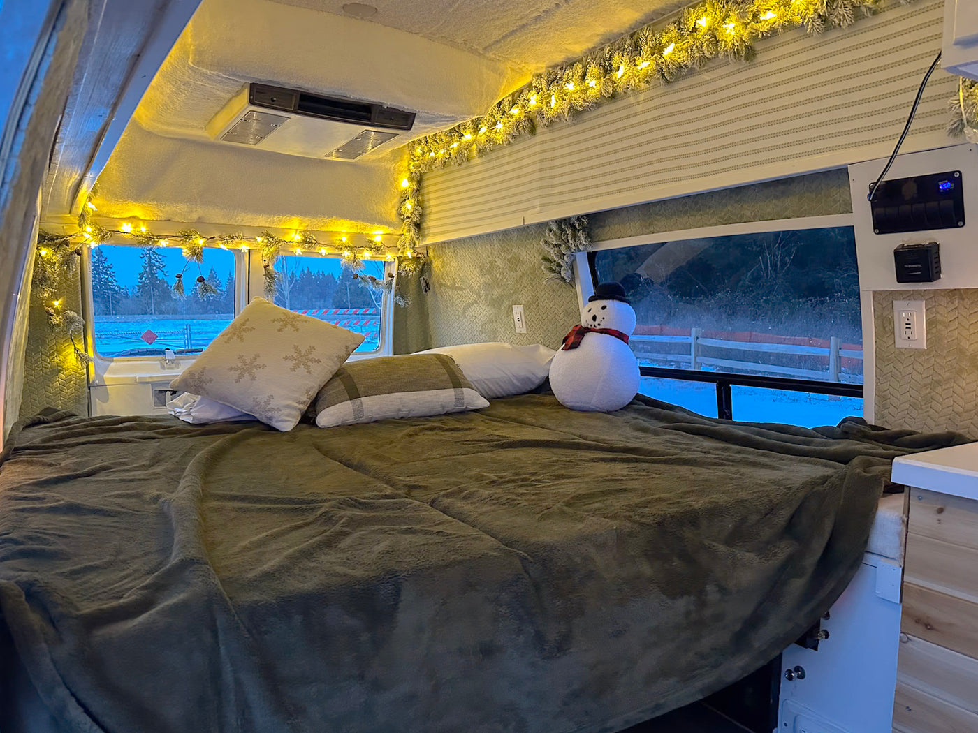  parked on asphalt near grass under a cloudy sky.|Cozy RV rental interior decorated for winter with festive lights — photo 12