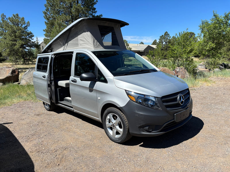 Silver Mercedes Metris pop-top camper van, side door open, on gravel. Ideal RV rental for outdoor adventures. — photo 10