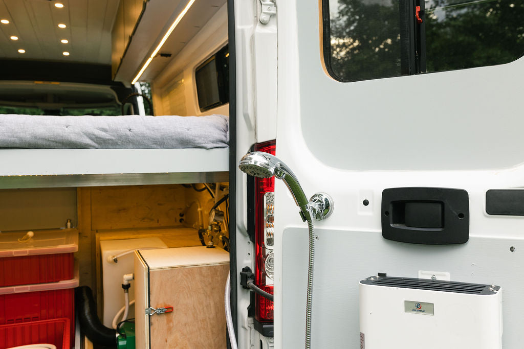 Inside this RV rental: a comfortable raised bed, ample storage, and a handy rear outdoor shower mounted on the door. — photo 5