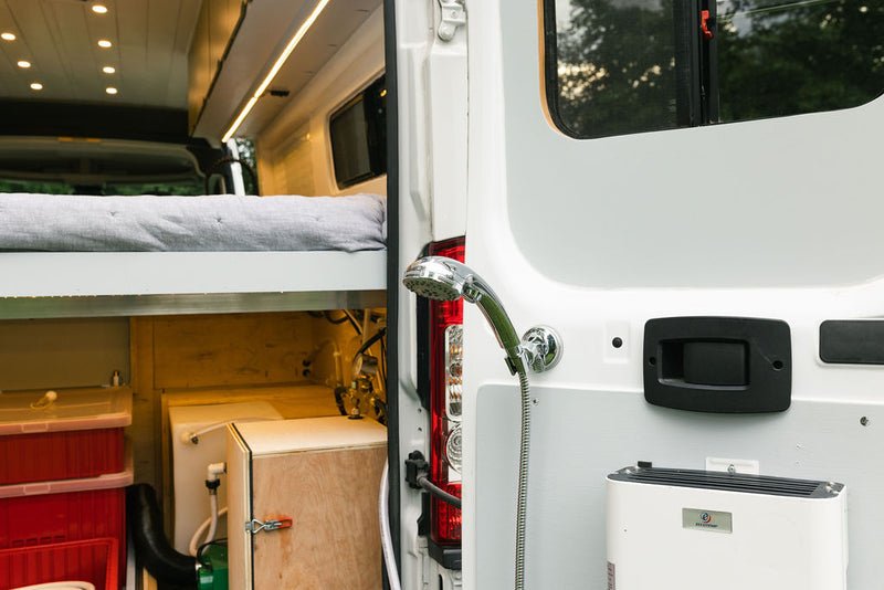 Inside this RV rental: a comfortable raised bed, ample storage, and a handy rear outdoor shower mounted on the door. — photo 5