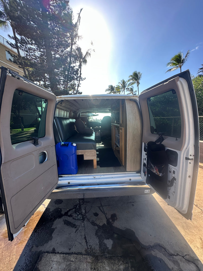 Sunny converted camper van RV rental with open rear doors, revealing its interior bed, storage, and a blue water jug. — photo 17