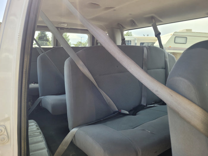 View from inside a passenger van with grey seats and seatbelts, offering a glimpse of an RV rental in the background.