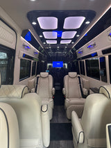Luxury RV rental interior: spacious cabin with cream leather captain's chairs, custom lighting, and entertainment system.