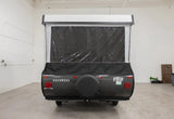 Rear view of a gray Rockwood pop-up RV rental, featuring a spare tire and clear vinyl window on the extended fabric section.