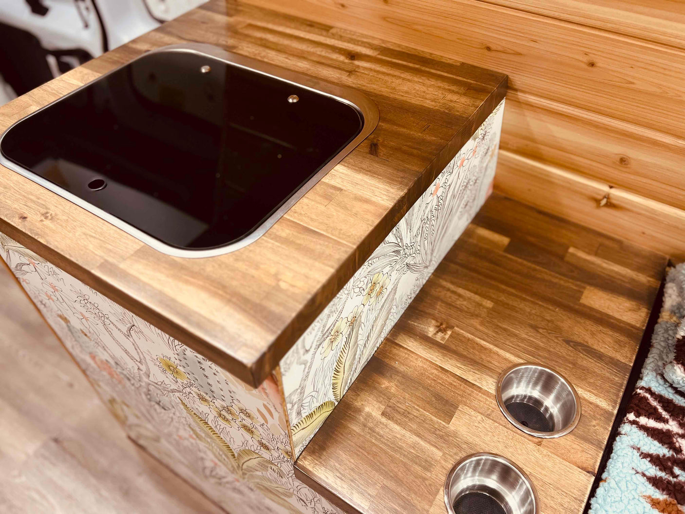 RV rental interior: A compact kitchen area with wooden countertops, an integrated induction cooktop, and built-in cup holders.
