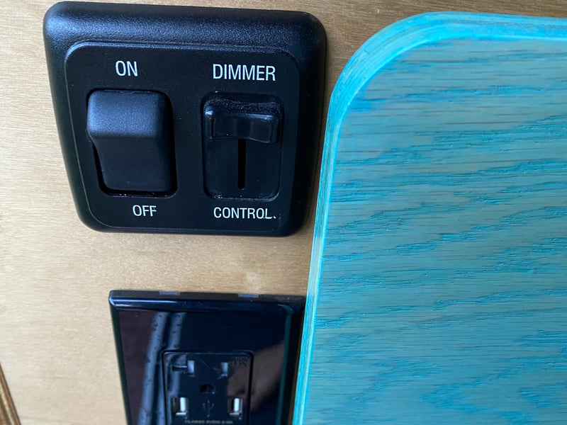 RV rental control panel: ON/OFF light switch, dimmer, and electrical outlet with USB next to a vibrant turquoise wood wall. — photo 13