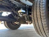 RV rental undercarriage: detailed view of heavy-duty rear suspension, incl. leaf springs, axle, and Falcon shocks. Vehicle mechanics insight.