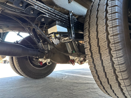 RV rental undercarriage: detailed view of heavy-duty rear suspension, incl. leaf springs, axle, and Falcon shocks. Vehicle mechanics insight.