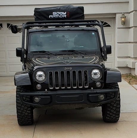 Rugged black Jeep Wrangler, equipped with a roof rack and adventure gear, ideal for your next RV rental adventure.