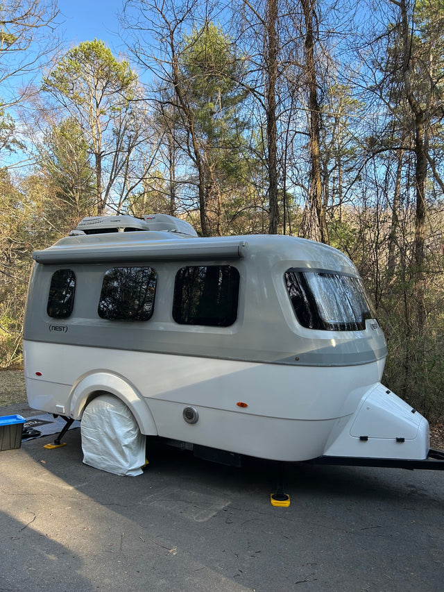 This Nest by Airstream travel trailer, an ideal rv rental, is set up at a wooded campsite, ready for an outdoor getaway.
