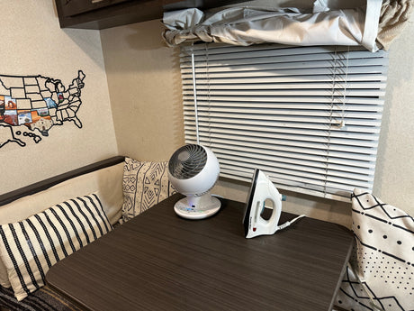 Cozy RV rental interior featuring a table with a small fan, an iron, decorative pillows, and a USA map on the wall.