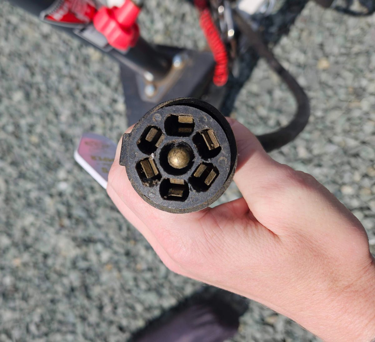 Close-up of a hand holding a 7-pin trailer connector, essential for an RV rental's lights and brakes. — photo 20