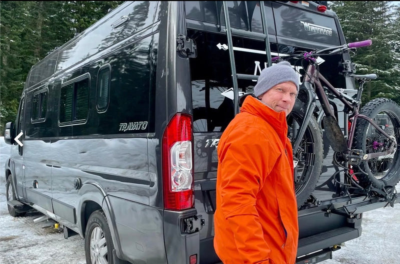 Man in orange jacket with a fat bike on a dark Winnebago Travato rv rental van in winter.|A gray Ram ProMaster RV rental — photo 1