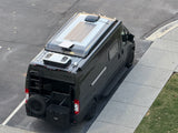 Sleek black Noovo RV rental, ready for adventure, featuring roof solar, ladder, and rear storage. Parked on asphalt.
