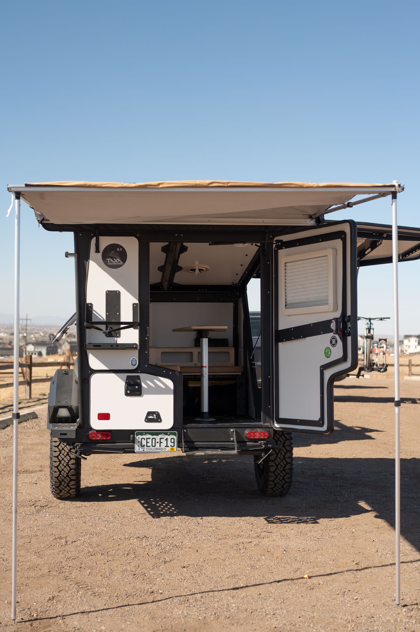 An open off-road TAXA camper with deployed awning, revealing its compact interior setup. Great for adventure or rv rental.