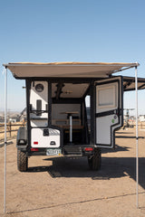 An open off-road TAXA camper with deployed awning, revealing its compact interior setup. Great for adventure or rv rental.