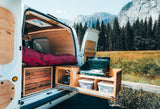 Adventure awaits! This custom camper van RV rental offers a comfortable sleeping area & pull-out kitchen with mountain views.