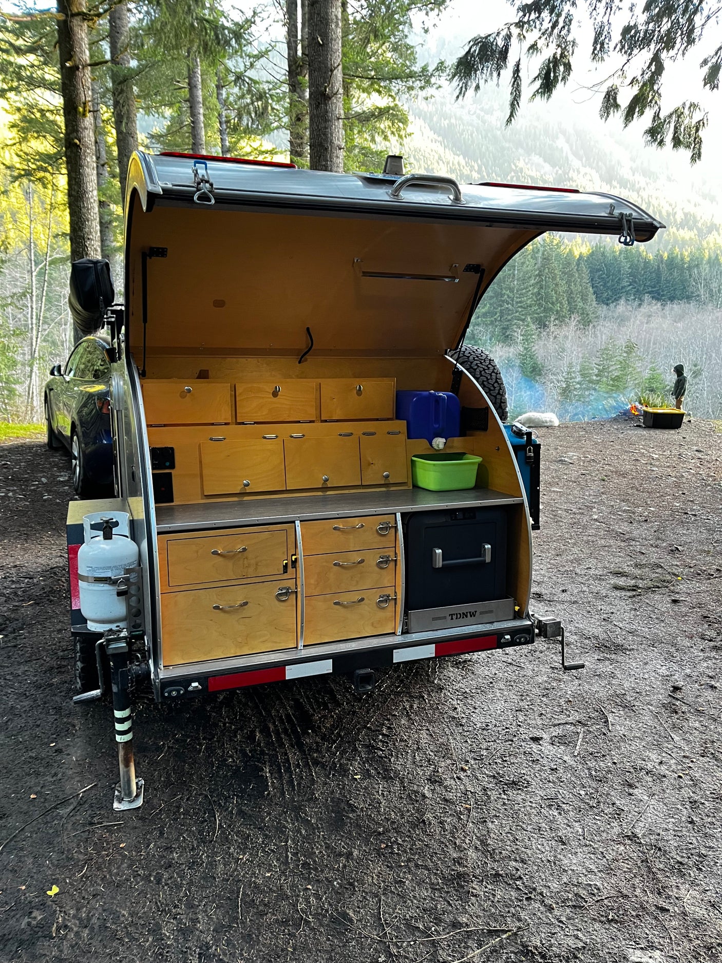 Teardrop camper outdoor kitchen setup at a scenic campsite, perfect for an RV rental adventure in nature.