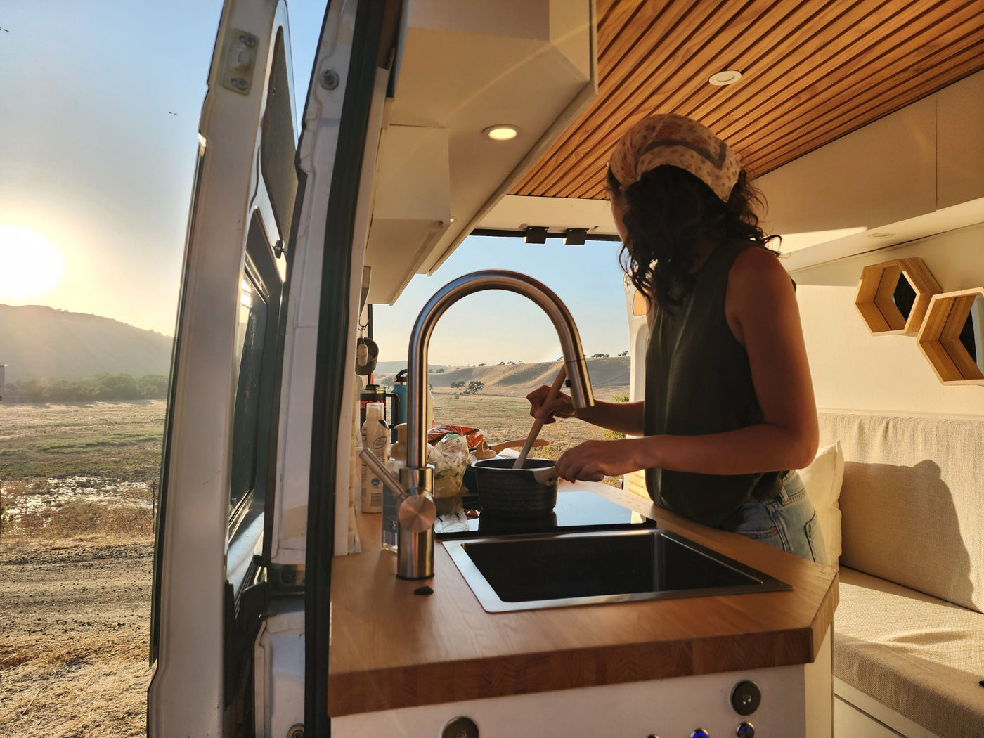  an RV rental is by the water under a blue sky.|Inside an rv rental: a modern camper van with wood accents