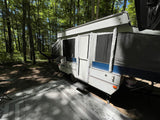 Pop-up camper RV rental ready for adventure at a sunny, wooded campsite. Perfect for outdoor getaways.