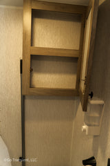 RV rental bathroom: Open wood cabinet with shelf and wall-mounted soap dispenser. Great for storage.