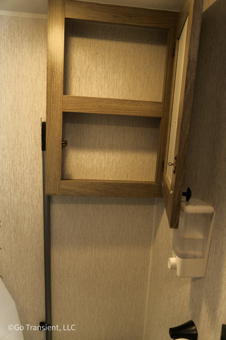 RV rental bathroom: Open wood cabinet with shelf and wall-mounted soap dispenser. Great for storage.